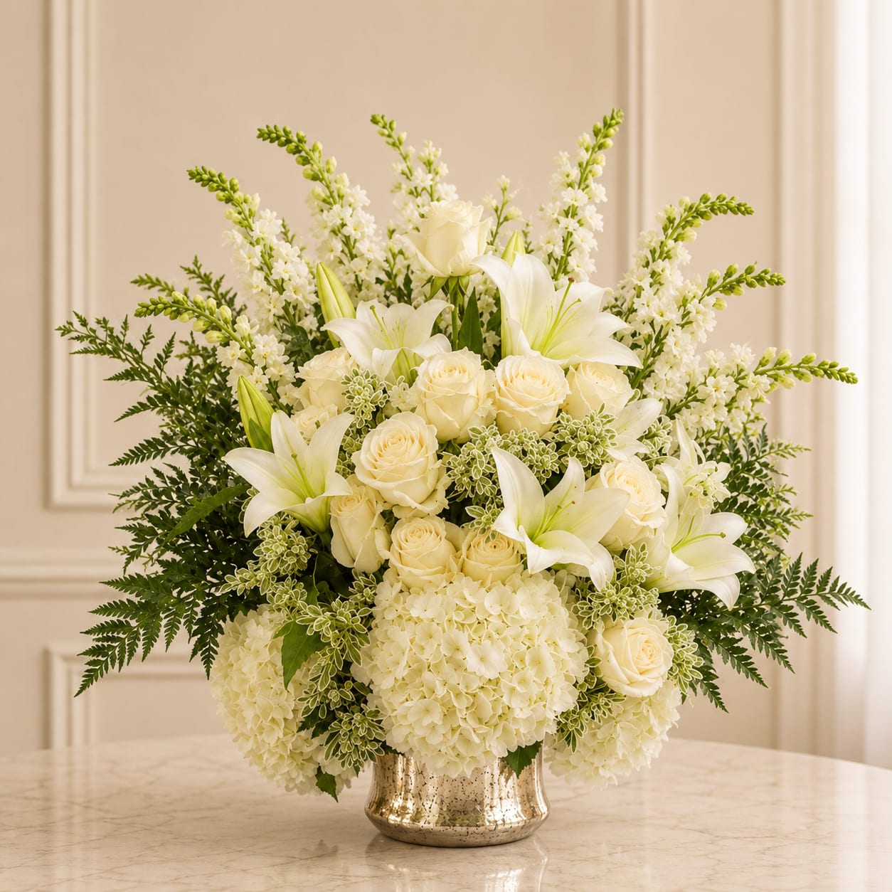 Beauty White - This elegant composition features lush white hydrangeas, creamy ivory roses, graceful white lilies, and delicate snapdragons layered with soft greenery and textured foliage.