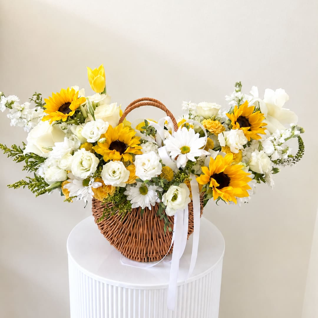 Basket of white and yellow flowers with a white ribbon