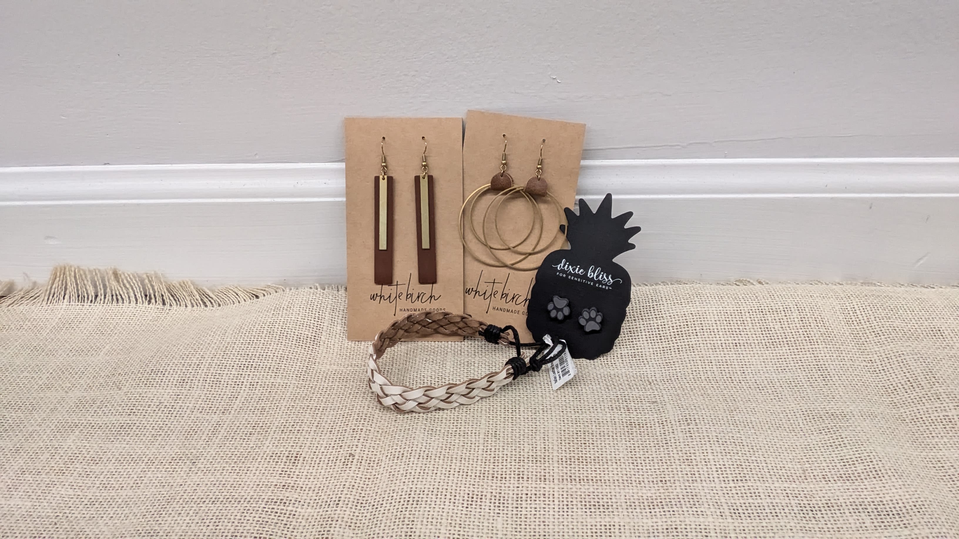Assorted earrings and braided bracelets displayed on cards and a table