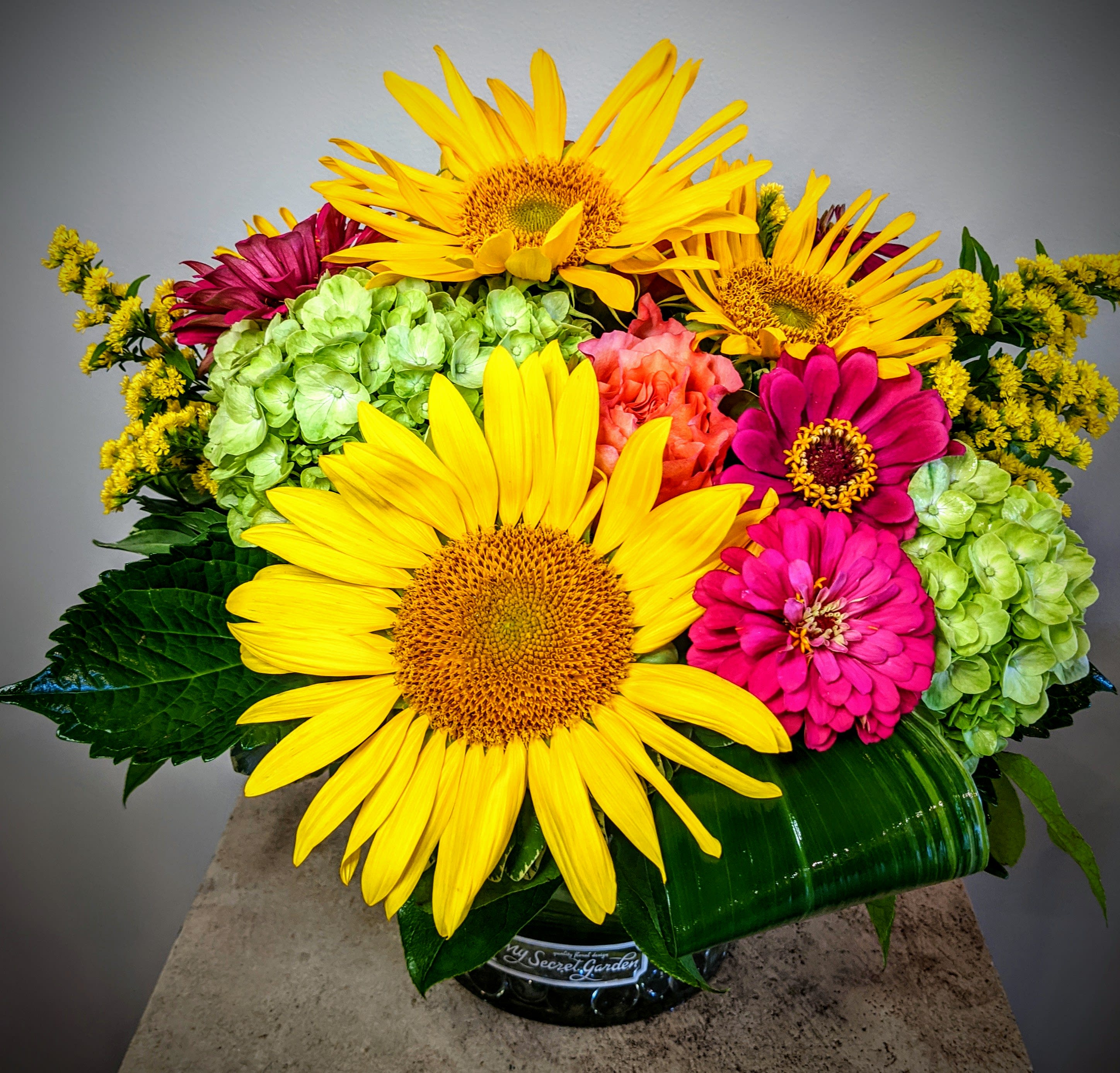 Bright bouquet with sunflowers, zinnias, and hydrangeas in a glass vase
