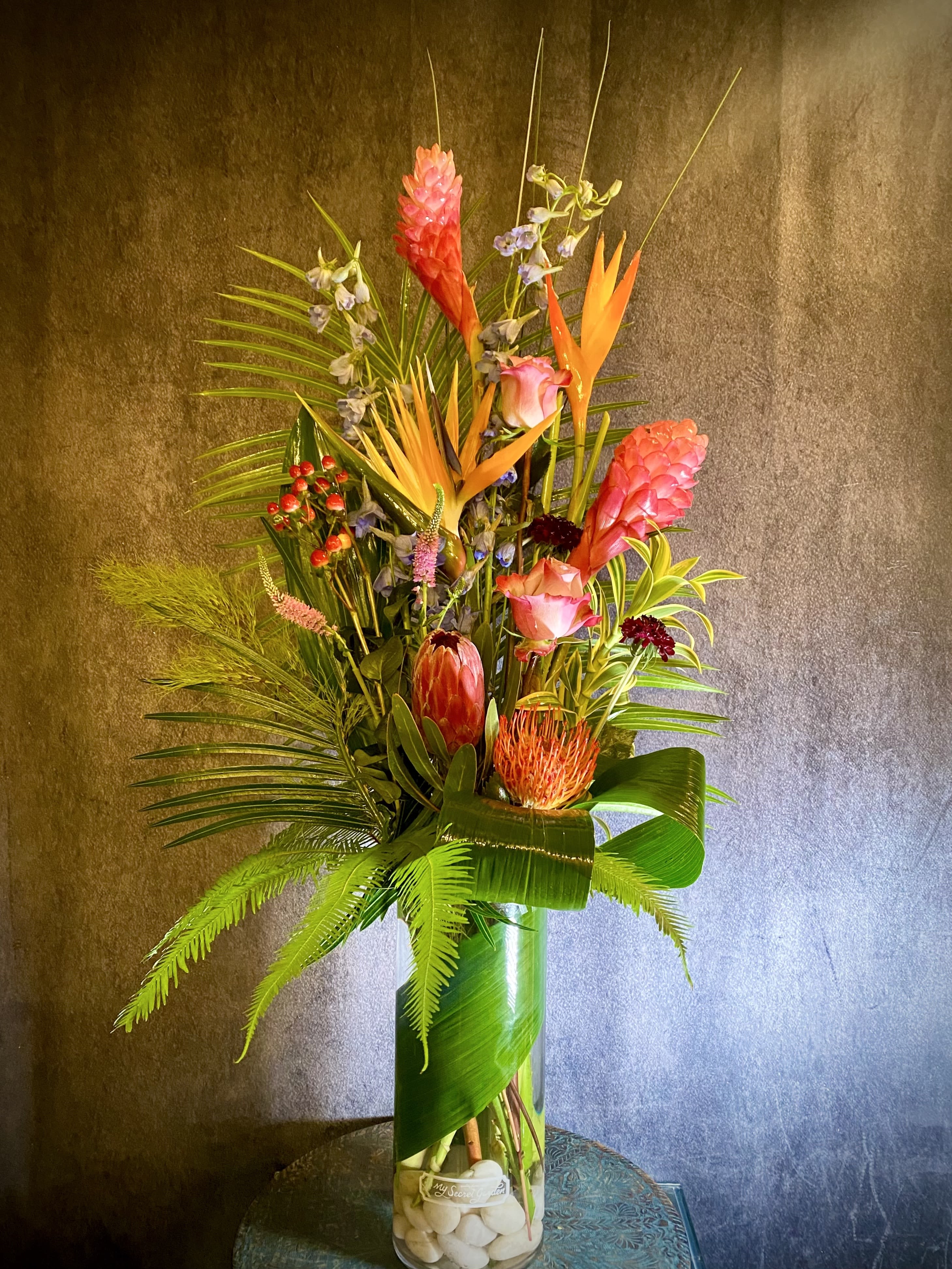 Tall tropical flower arrangement in a clear glass vase