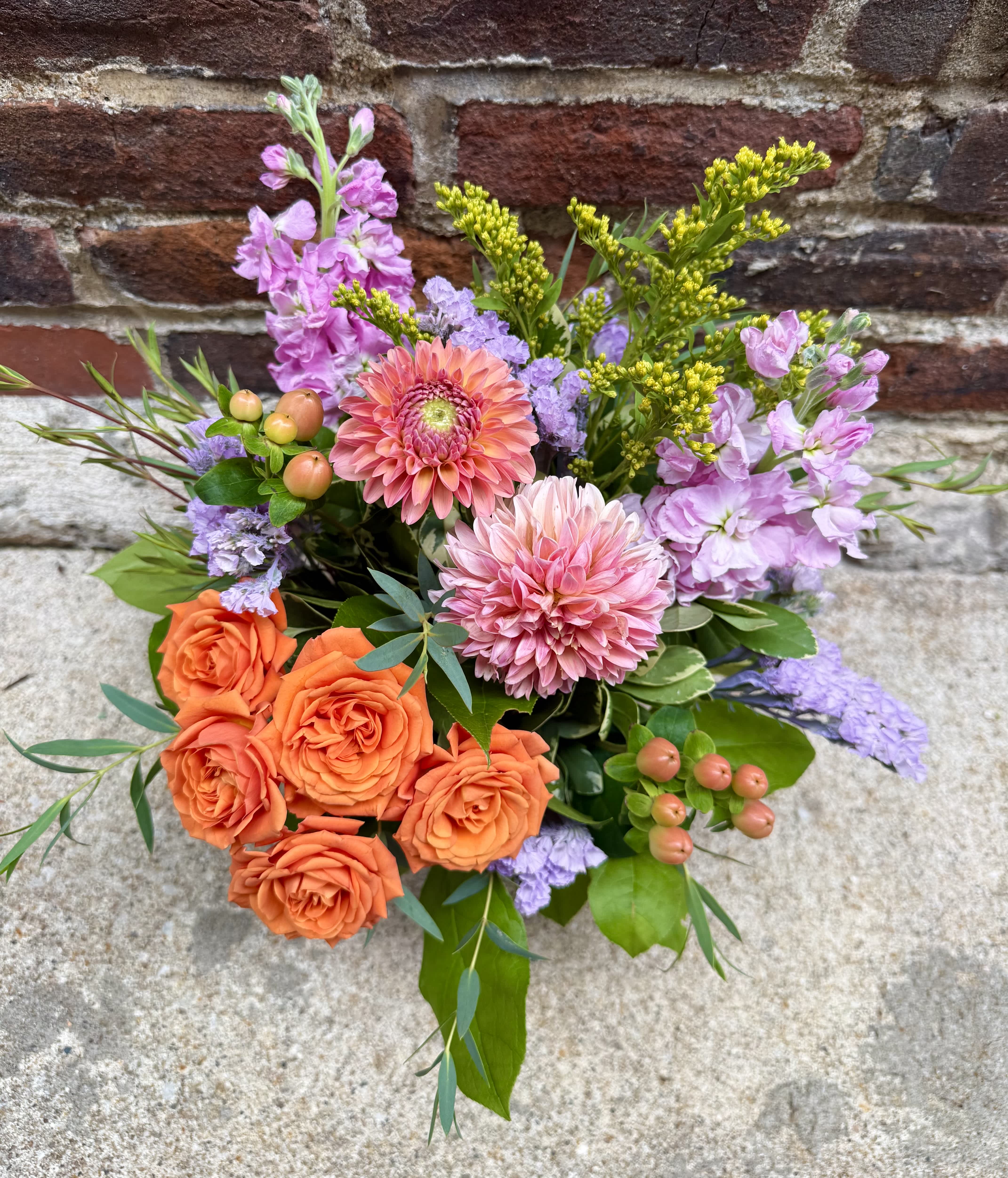 Bouquet of orange roses, pink dahlias, and lavender flowers