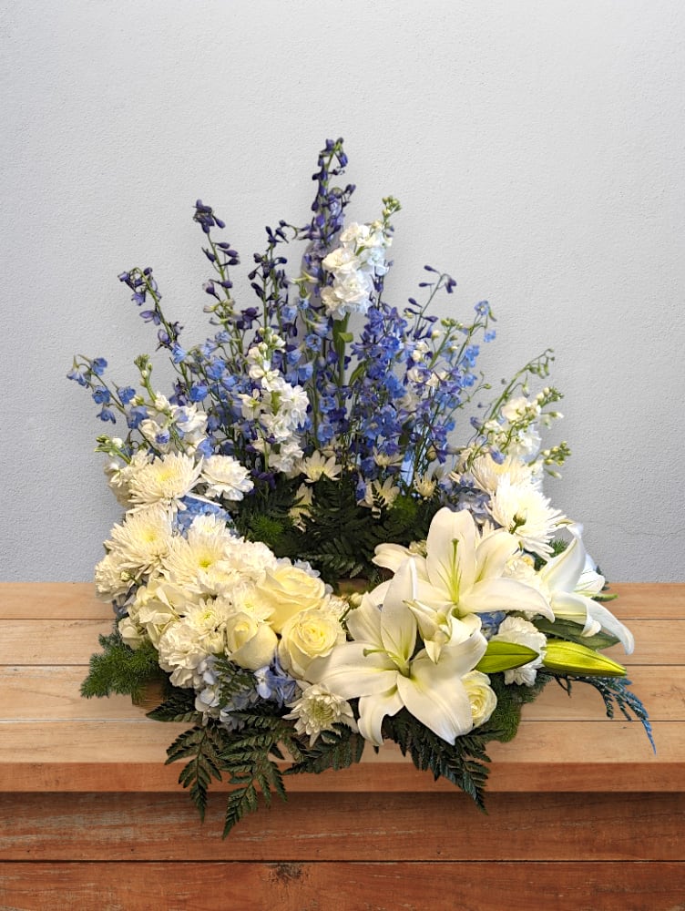 White lilies and blue flowers in a low floral arrangement