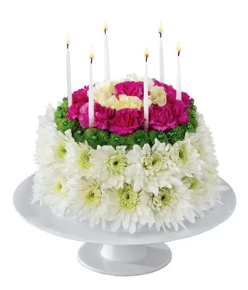 Round floral cake with candles and pink, white, and green flowers