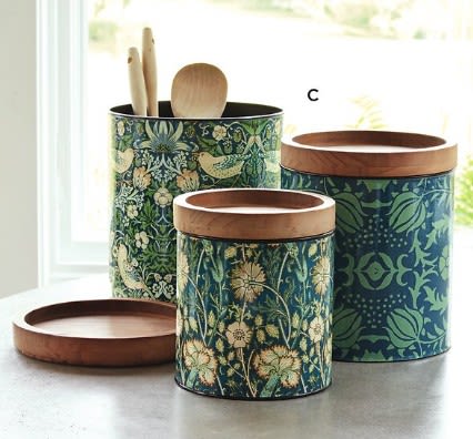 Three patterned canisters with wooden lids and utensils