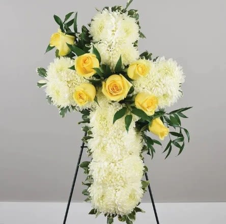 White floral cross with yellow roses on a stand