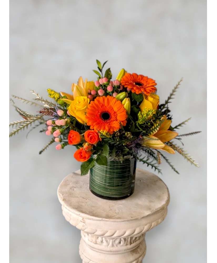 Orange and yellow mixed flower arrangement in a glass vase