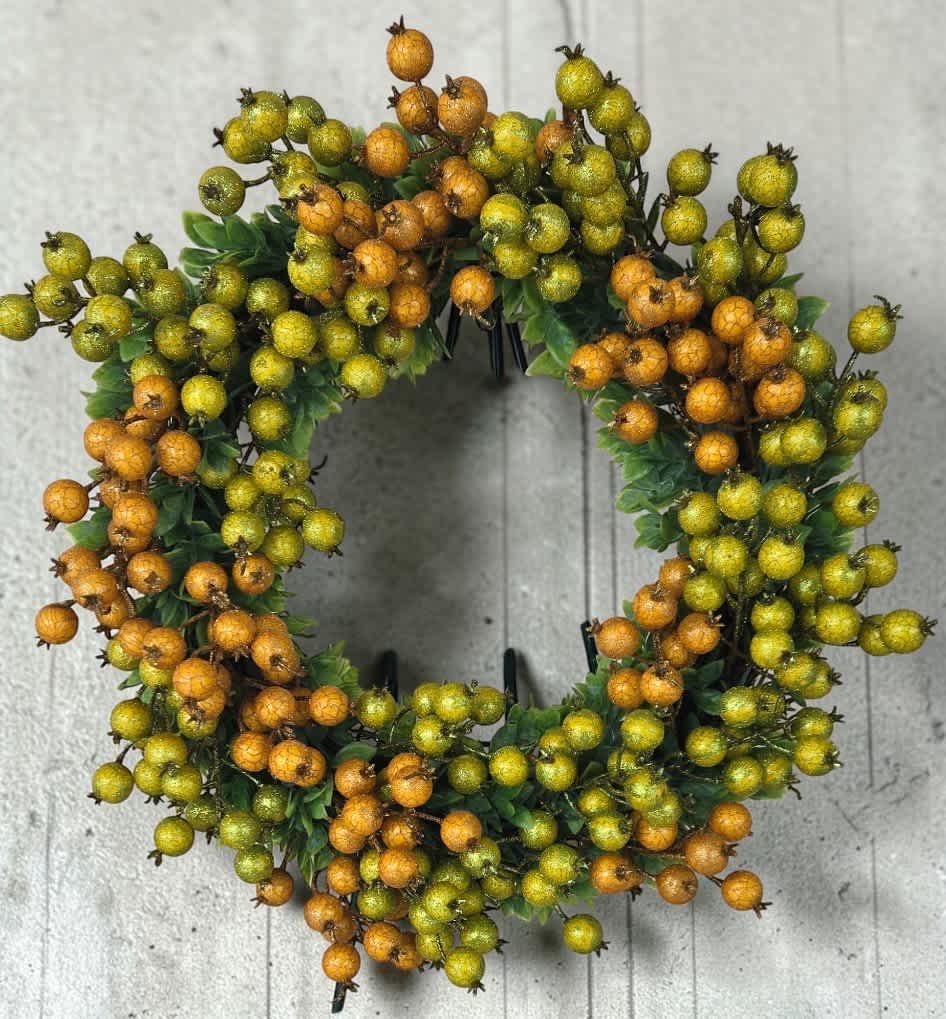 Round wreath of orange and green berries on a gray background