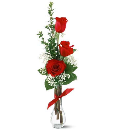 Three red roses in a clear glass vase with baby's breath and a red ribbon
