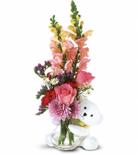 Pink and red flower arrangement with a white teddy bear in a glass vase