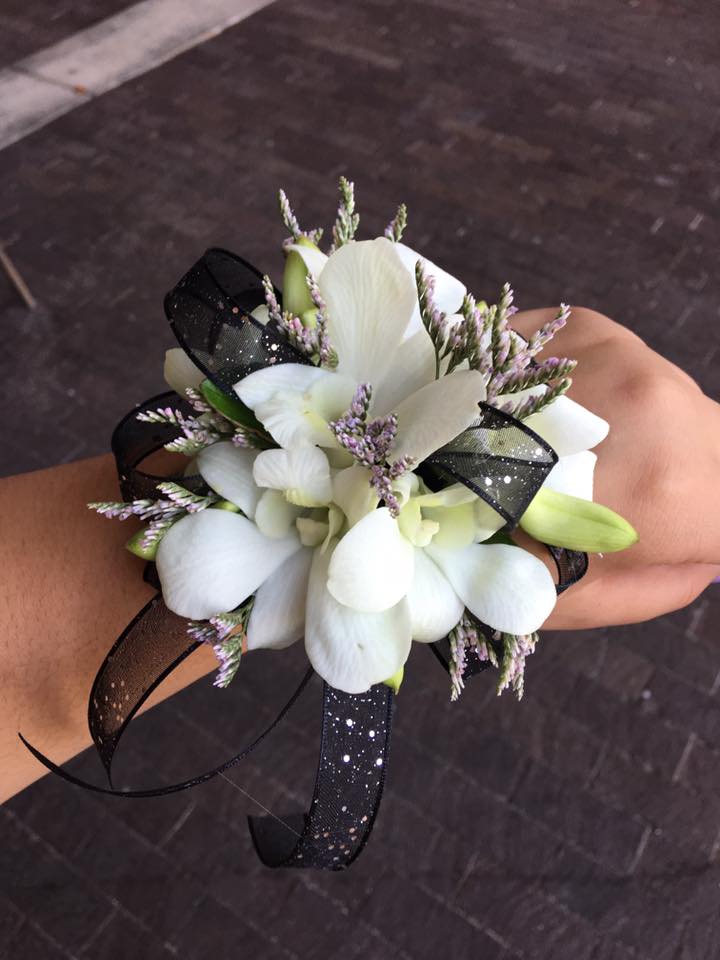 White orchid corsage with black ribbon on a wrist