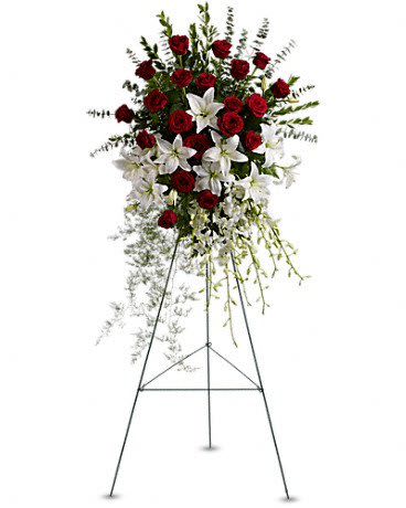 Standing floral spray of red roses and white lilies on a metal easel