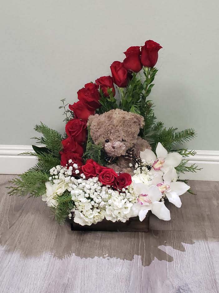 Red roses and white orchids arranged with a teddy bear in a black box