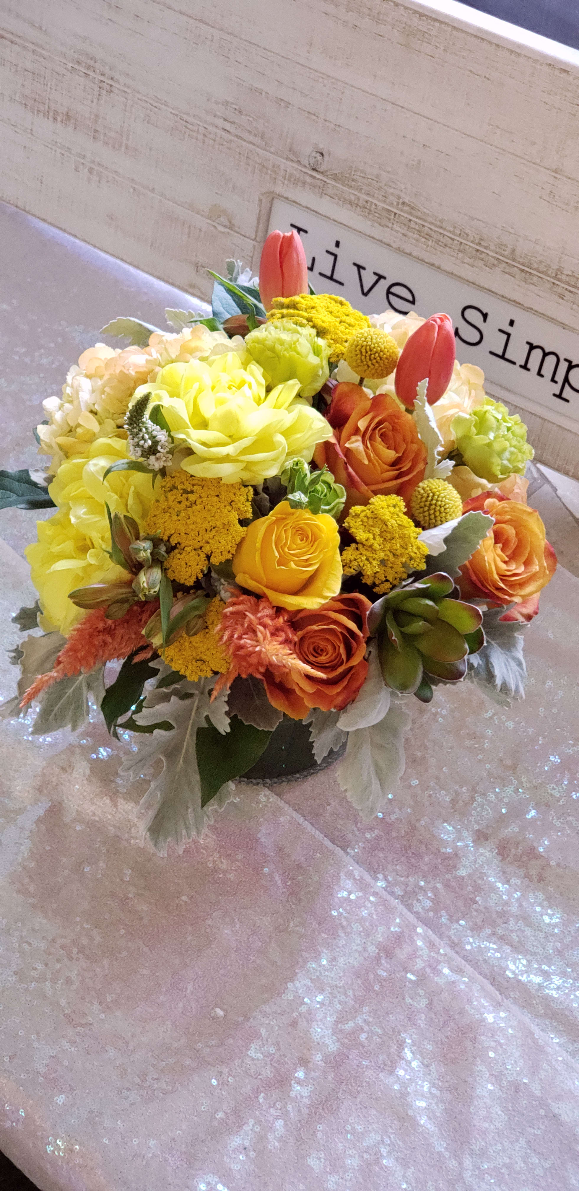 Yellow and orange flower arrangement in a low vase
