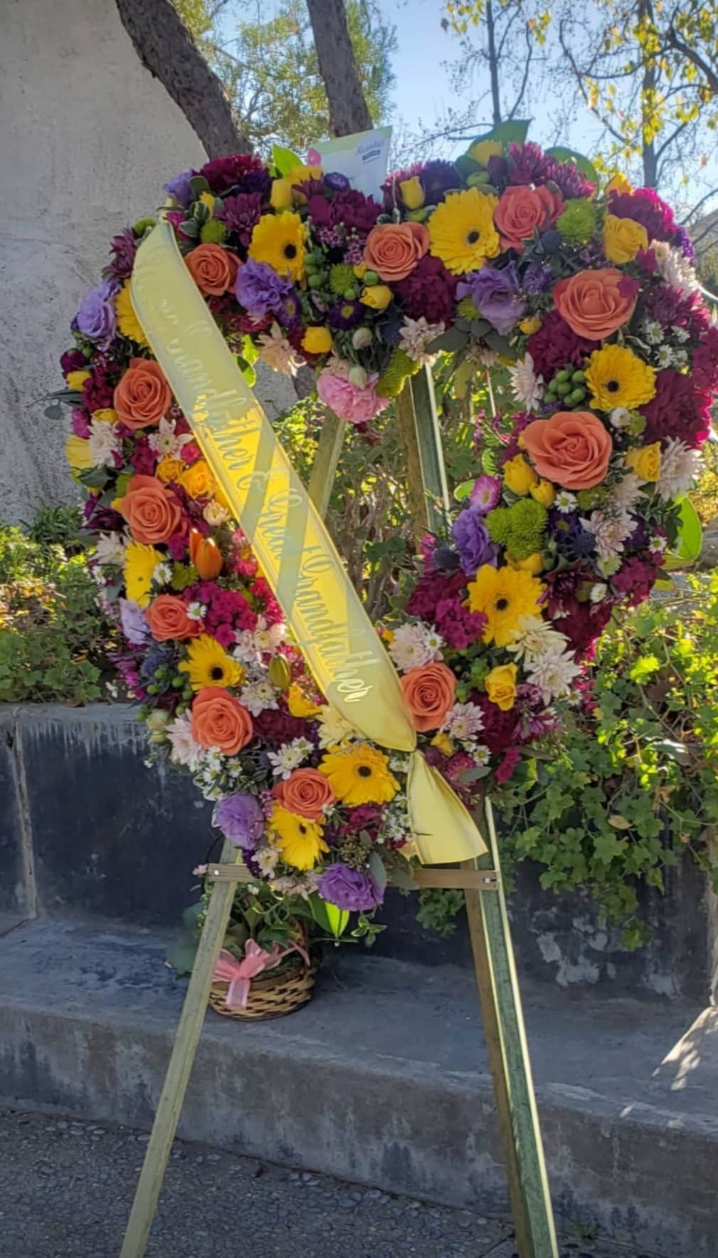 Heart-shaped floral wreath on an easel with a yellow ribbon