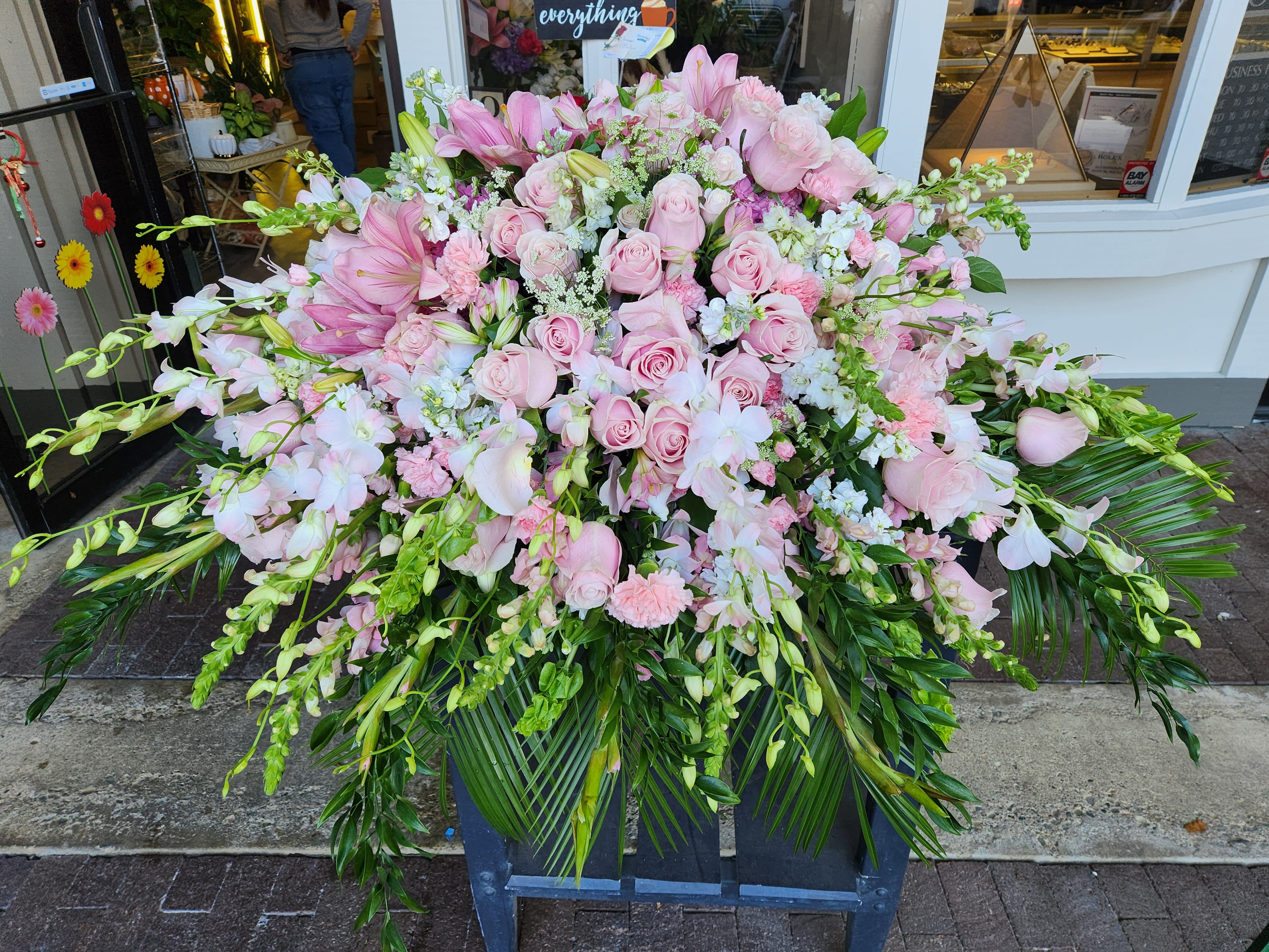 Large pink floral arrangement with roses and orchids in a stand