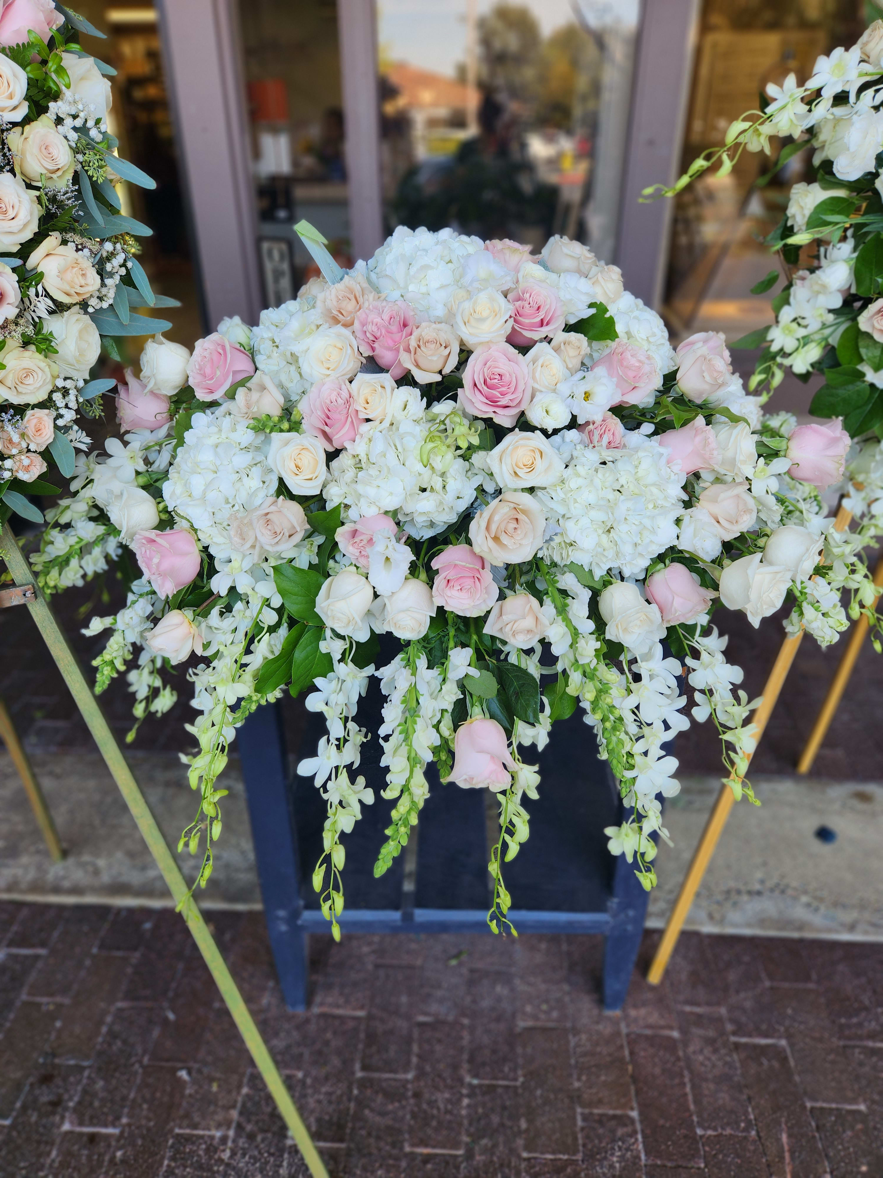 Large pastel floral arrangement with pink and white roses and cascading white blooms