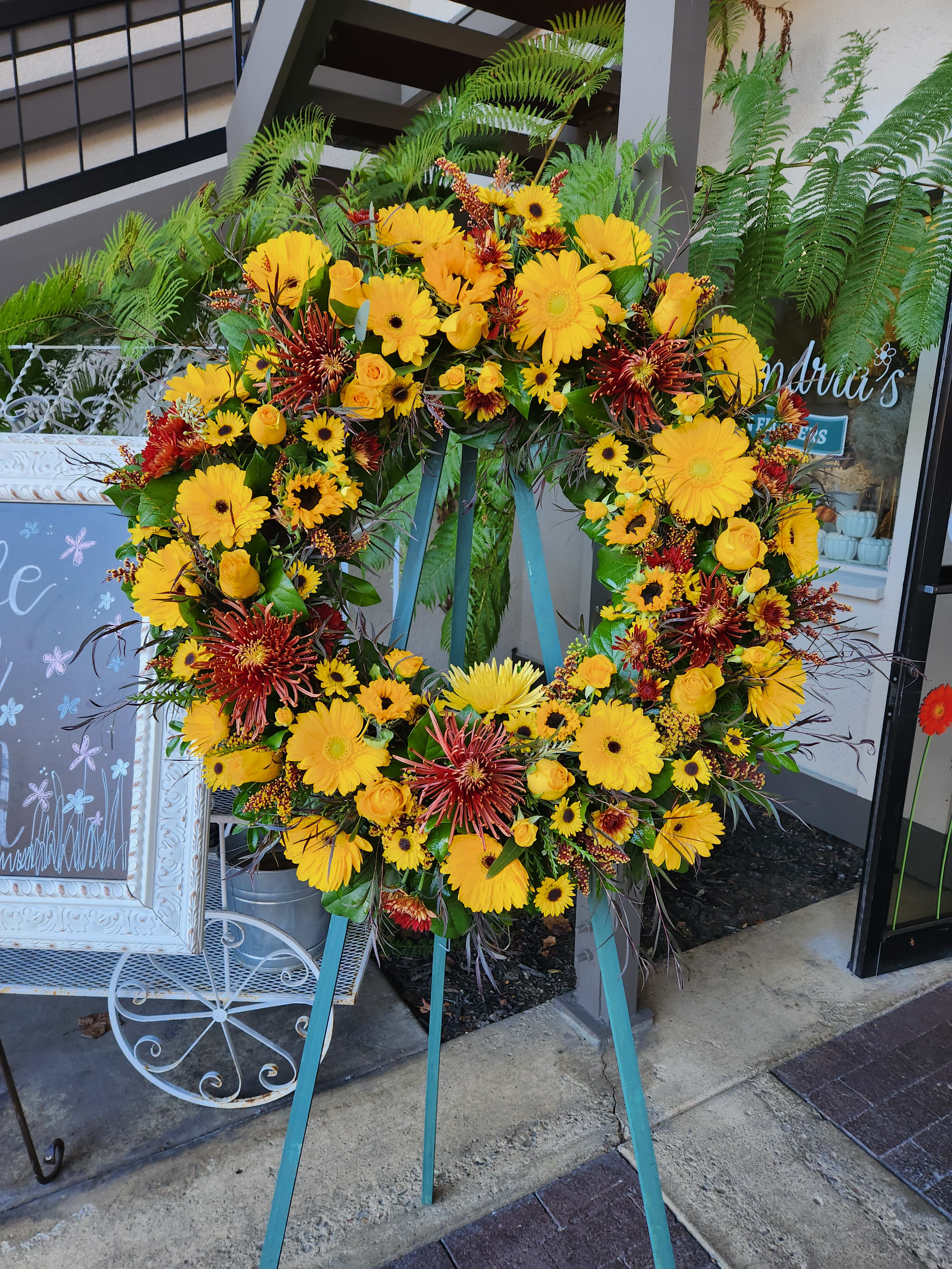 Large yellow and red floral wreath on a stand