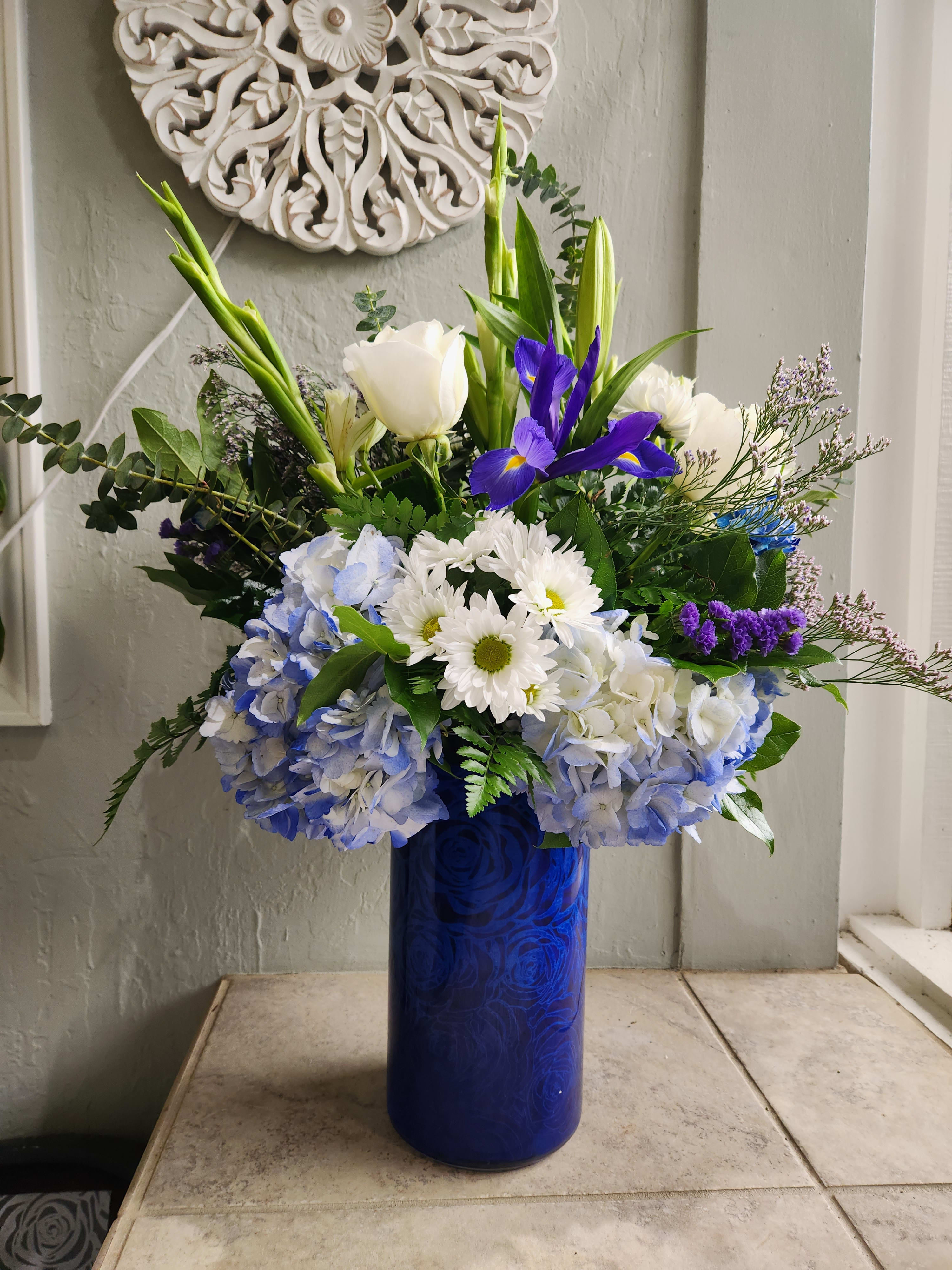 Blue and white floral arrangement in a tall cobalt vase