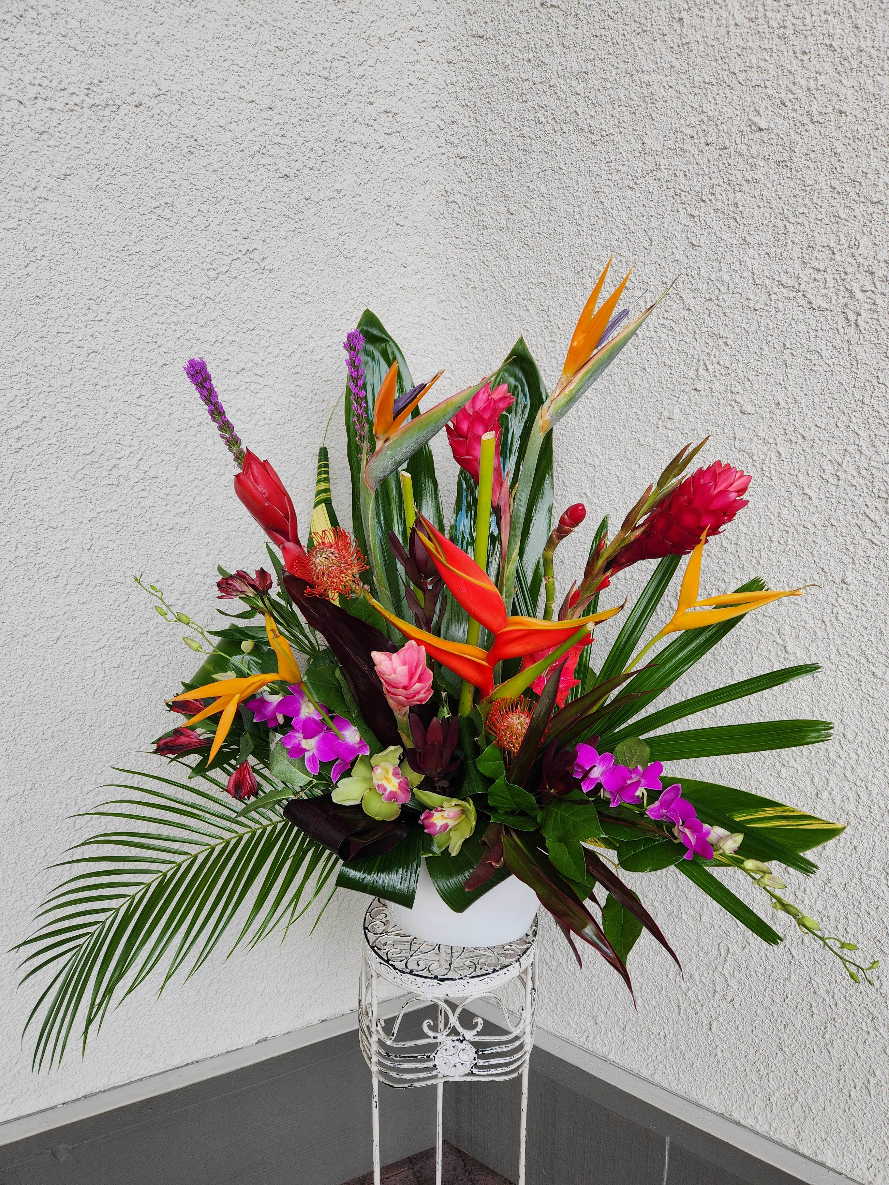Tropical flower arrangement with bird of paradise and orchids in a white vase
