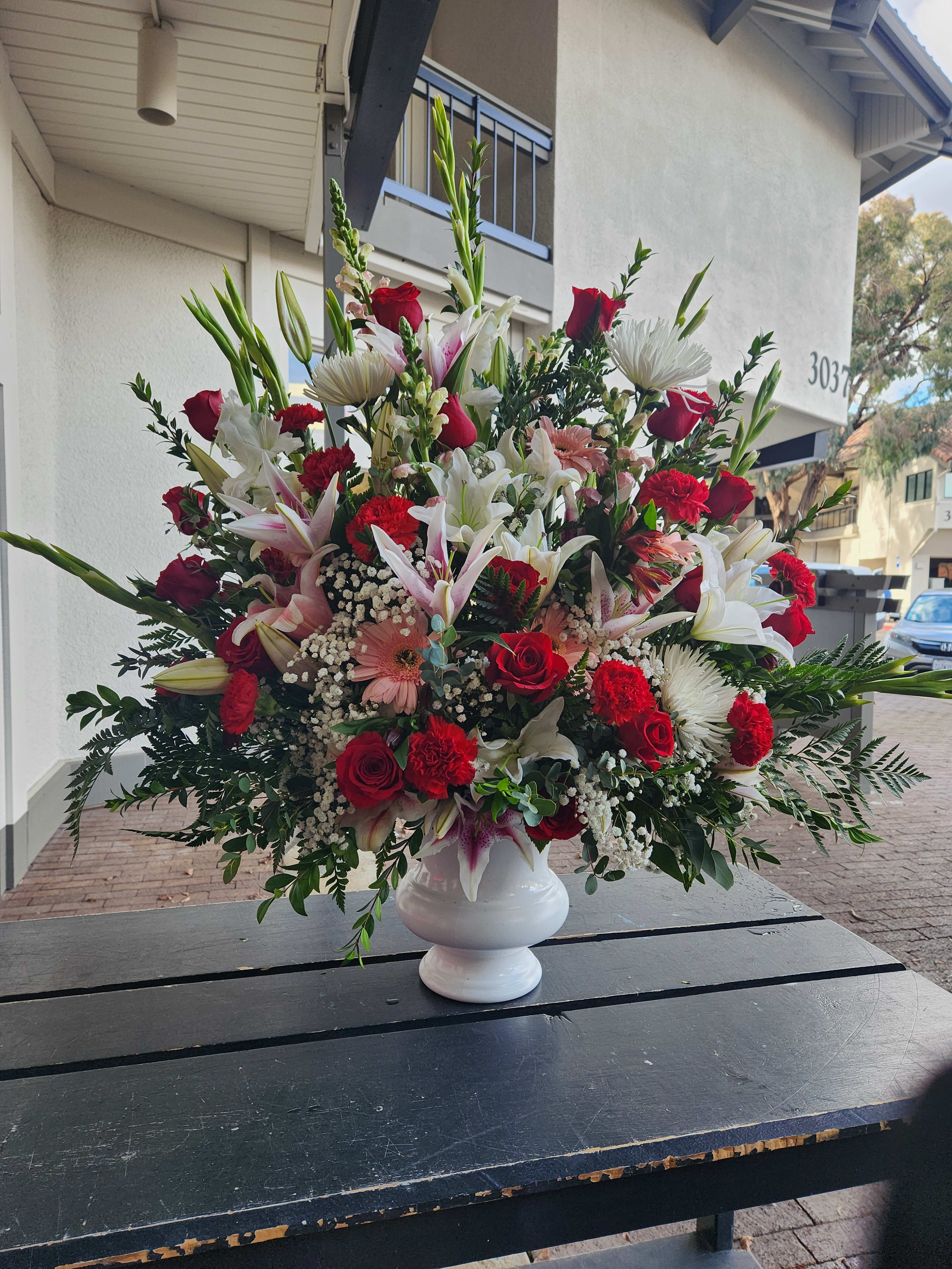 Large mixed bouquet in a white urn vase with red, white, and pink flowers