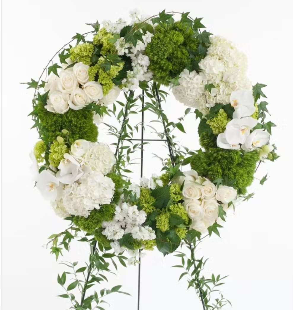 White and green floral wreath on a stand with orchids and roses