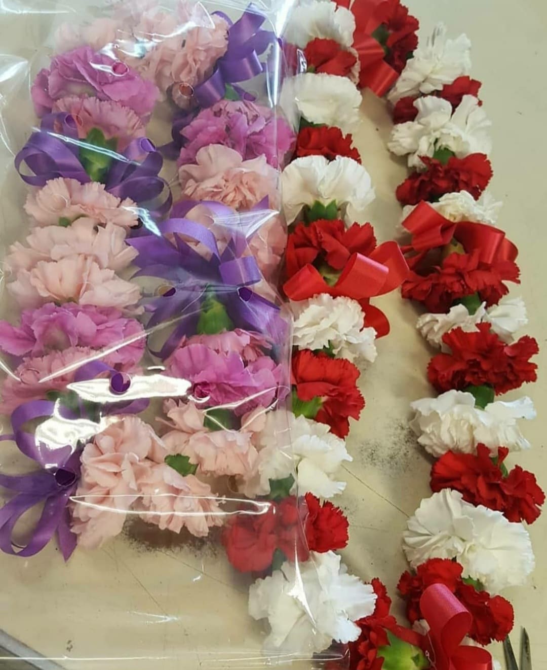 Bundles of pink, red, and white carnations tied with purple and red ribbons