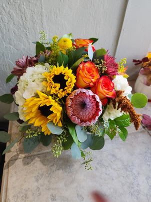 Mixed bouquet with sunflowers, orange roses, and white blooms