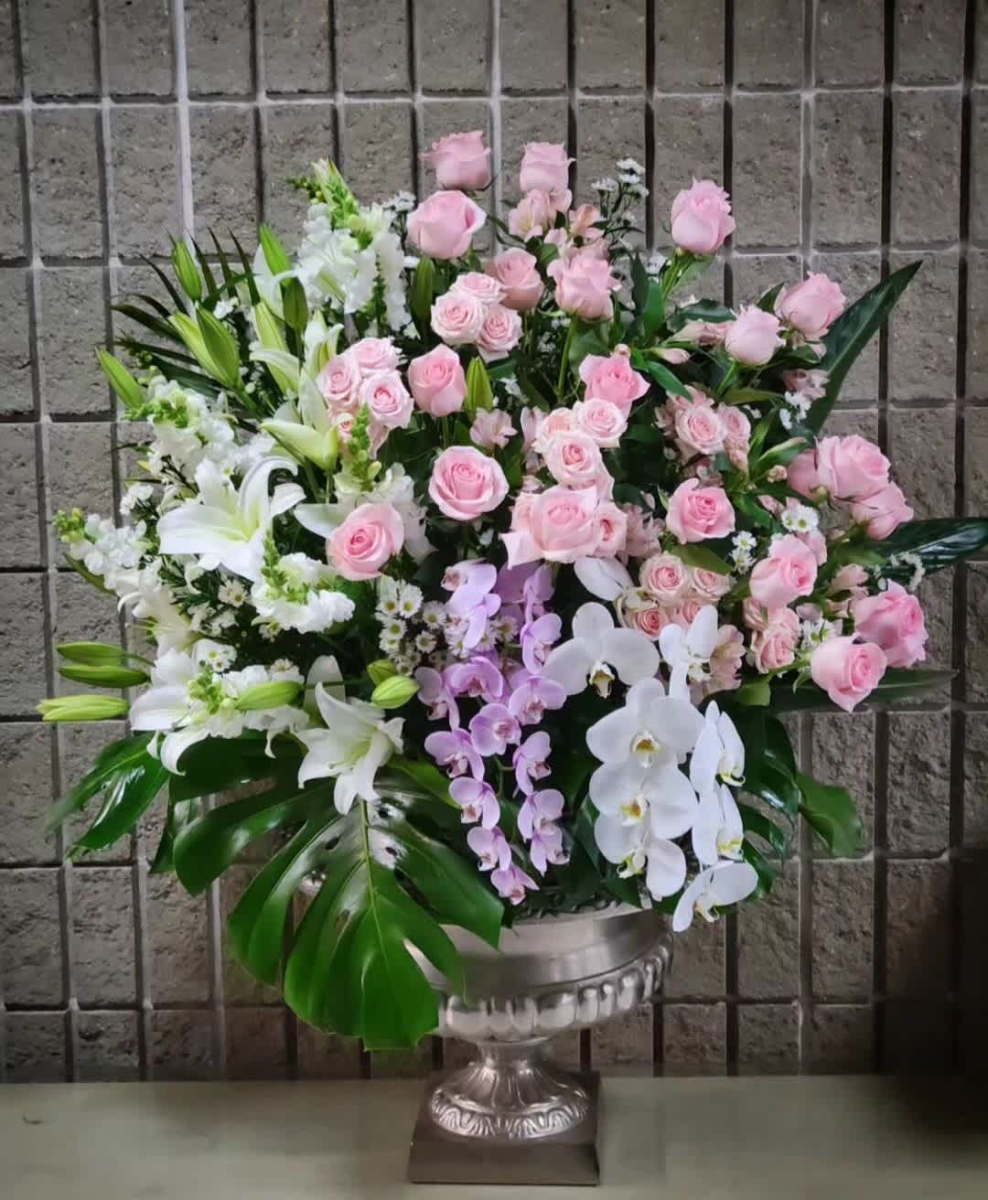 Large pink and white floral arrangement in a silver urn vase
