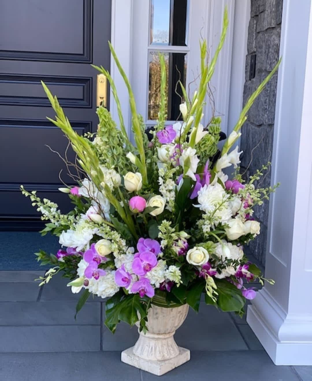 Tall floral arrangement with white and purple blooms in a pedestal urn