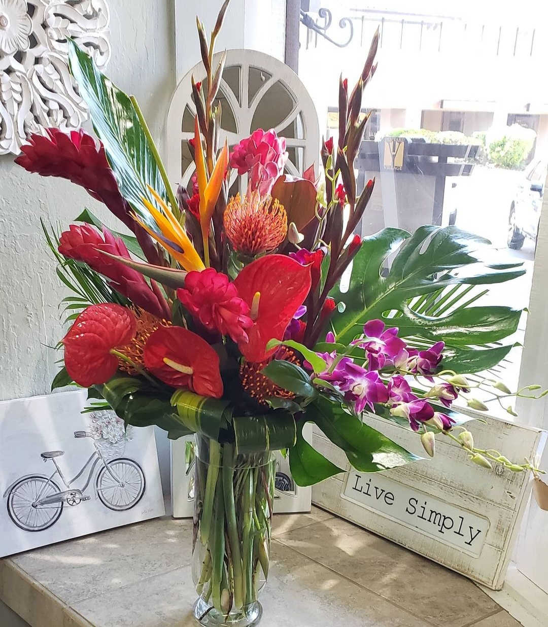 Tropical bouquet in a clear glass vase with red and purple flowers