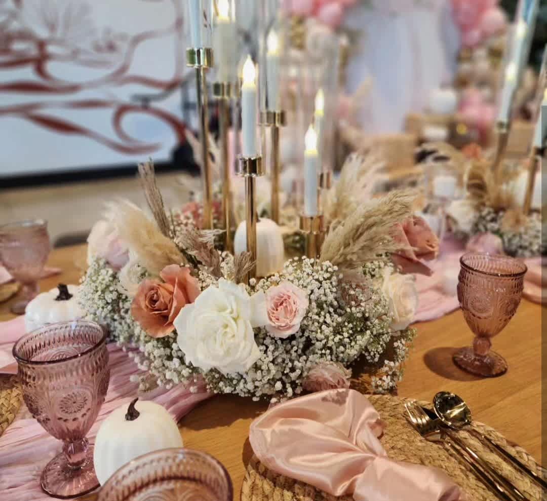 Low floral centerpiece with roses, baby's breath, and candles on a table