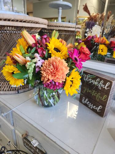 Bright mixed bouquet with sunflowers, lilies, and gerbera daisies in a glass vase