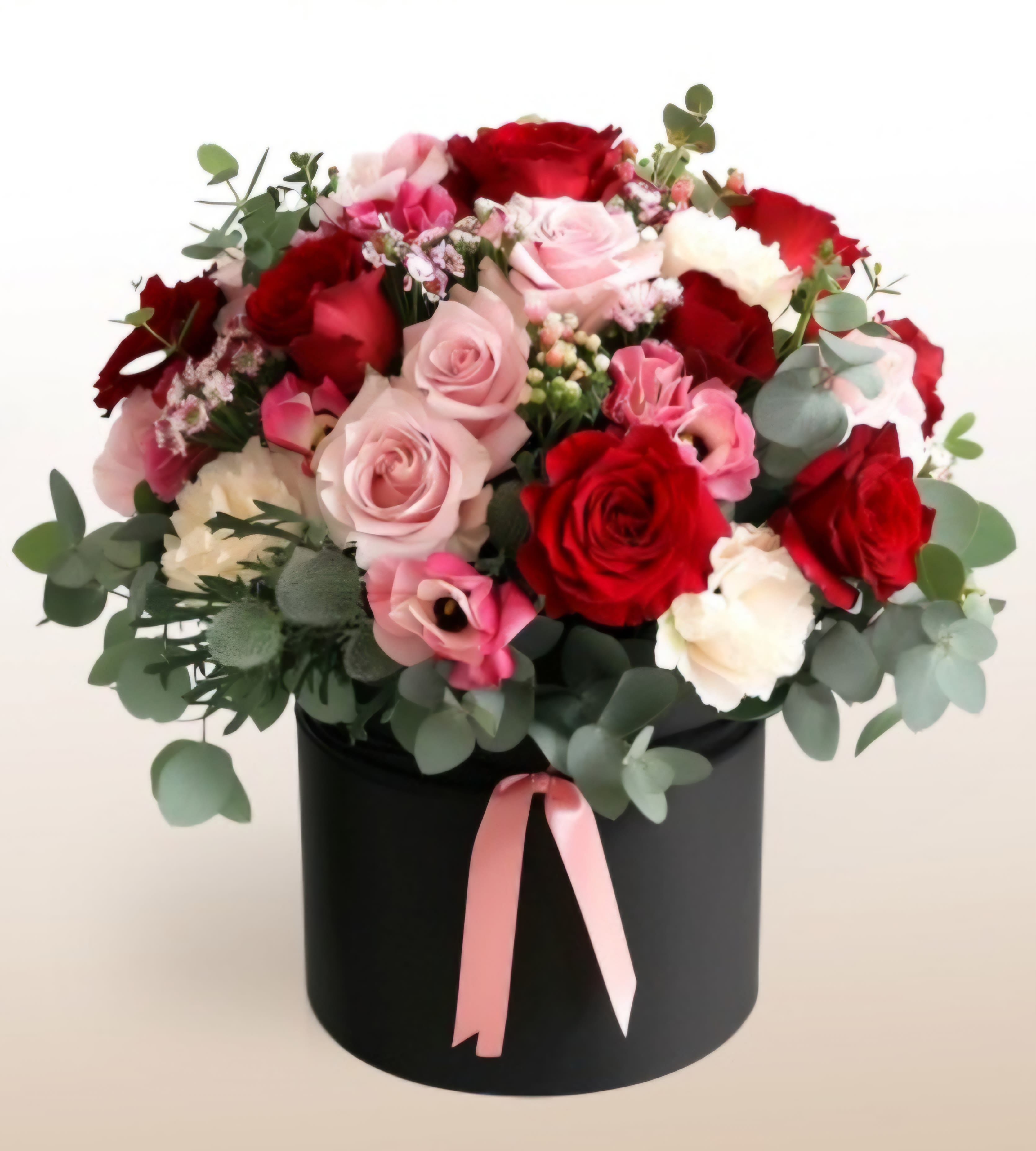 Bouquet of red and pink roses in a black hat box with a pink ribbon