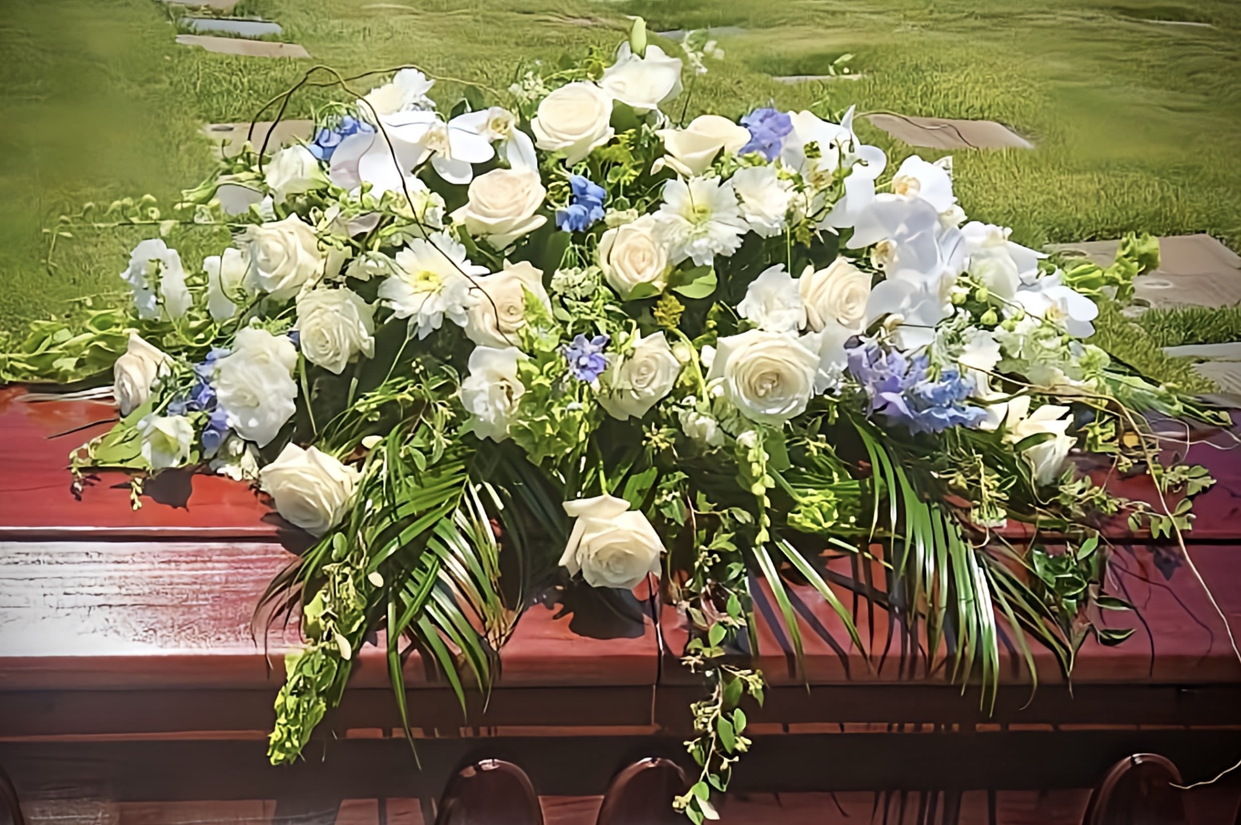 Large white floral casket spray with blue accents