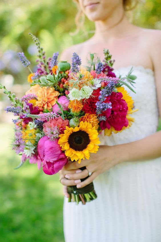 Bride holding a colorful bouquet with sunflowers and mixed blooms