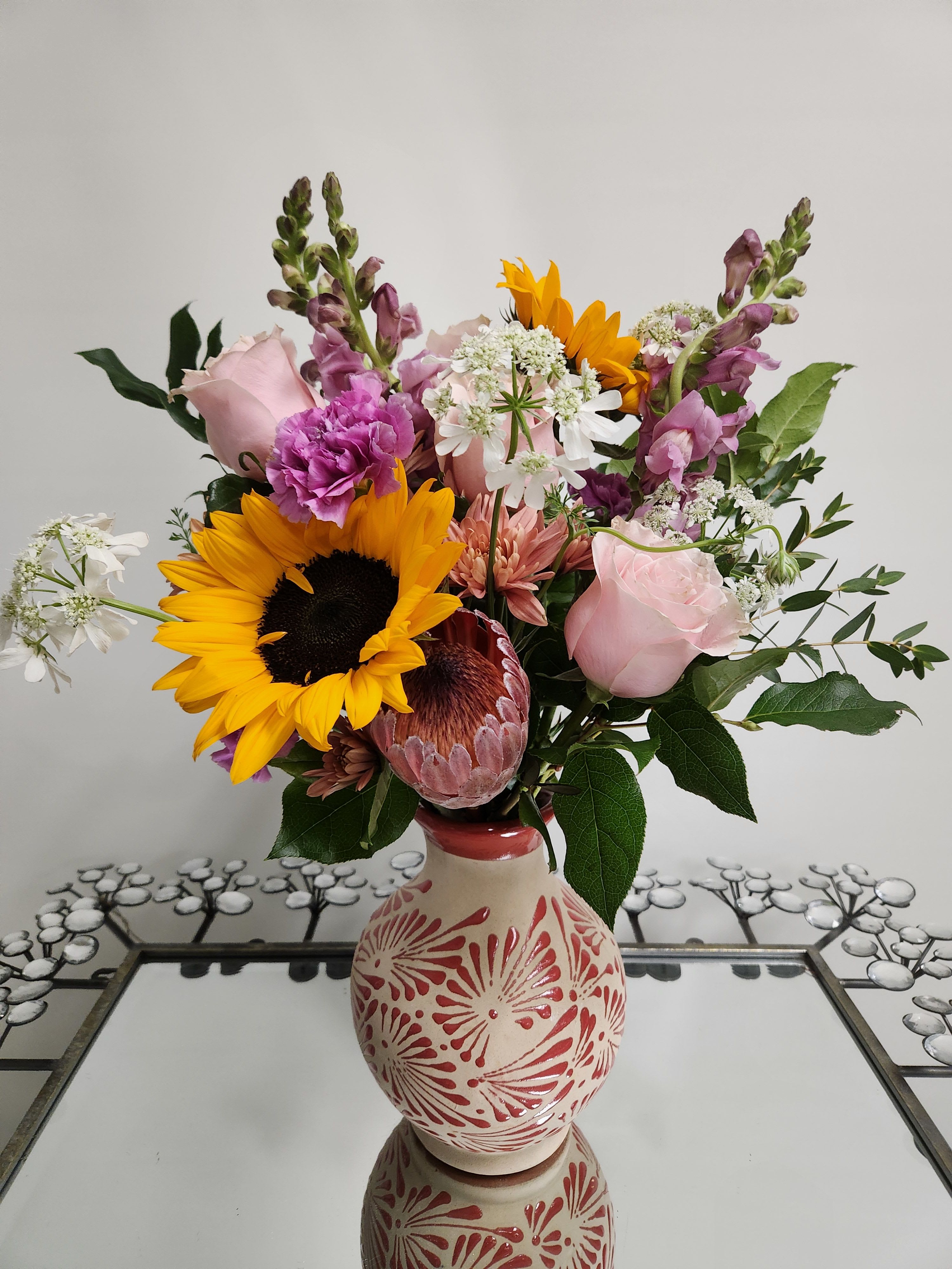 Mixed bouquet with sunflowers, pink roses, and purple blooms in a decorative vase