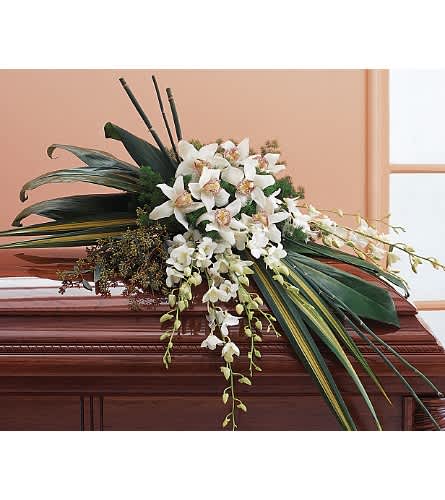 White orchid arrangement on a casket with long green leaves