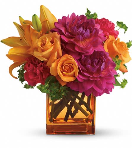 Orange and magenta flowers arranged in a square glass vase