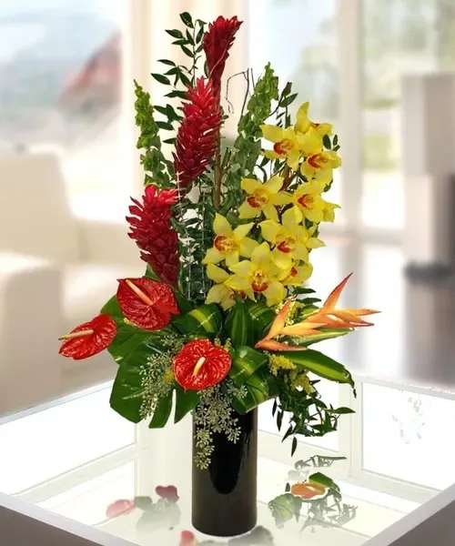 Tropical flower arrangement with red anthuriums and yellow orchids in a black vase