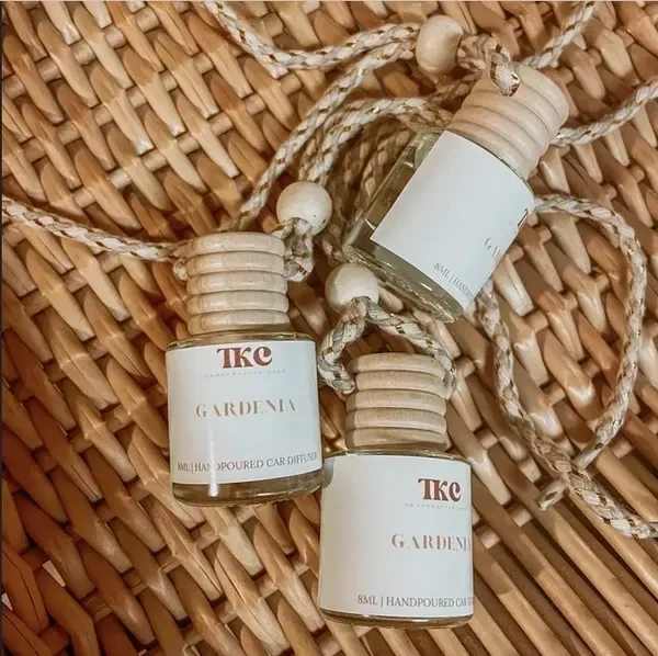 Three small gardenia car diffuser bottles on a woven mat