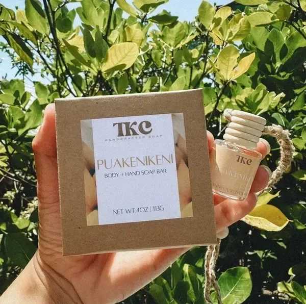 Hand holding a boxed soap bar and a small bottle outdoors