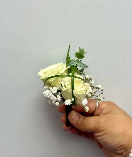 Small white rose boutonniere with baby's breath and greenery