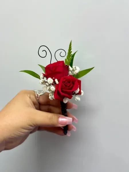 Red rose boutonniere with baby's breath and green leaves