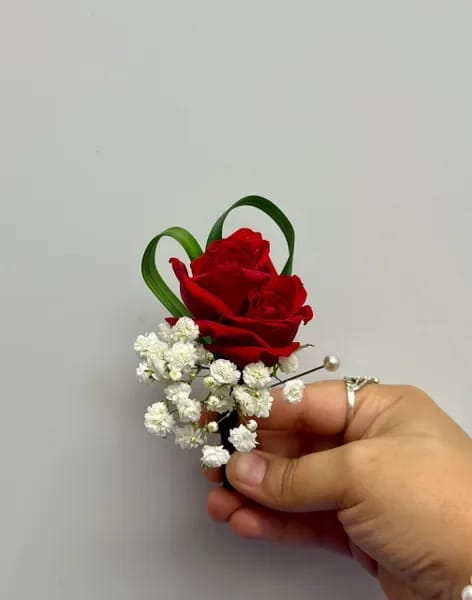 Red rose boutonniere with white baby's breath and green loops