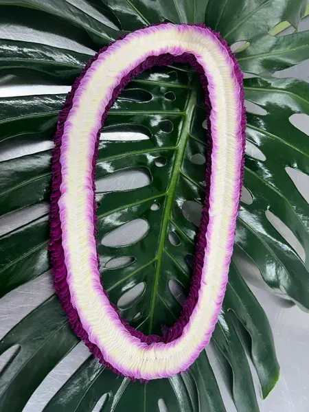 Purple-and-white floral lei on large tropical leaves