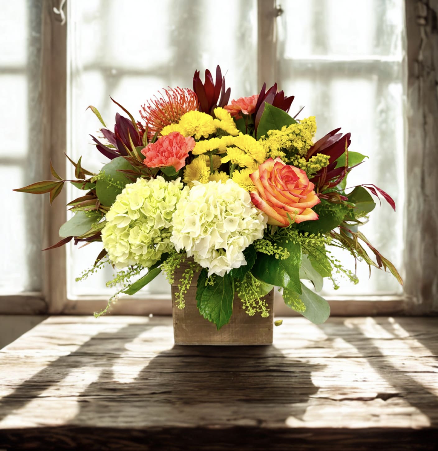 Mixed bouquet in a square wooden vase with hydrangeas, roses, and chrysanthemums