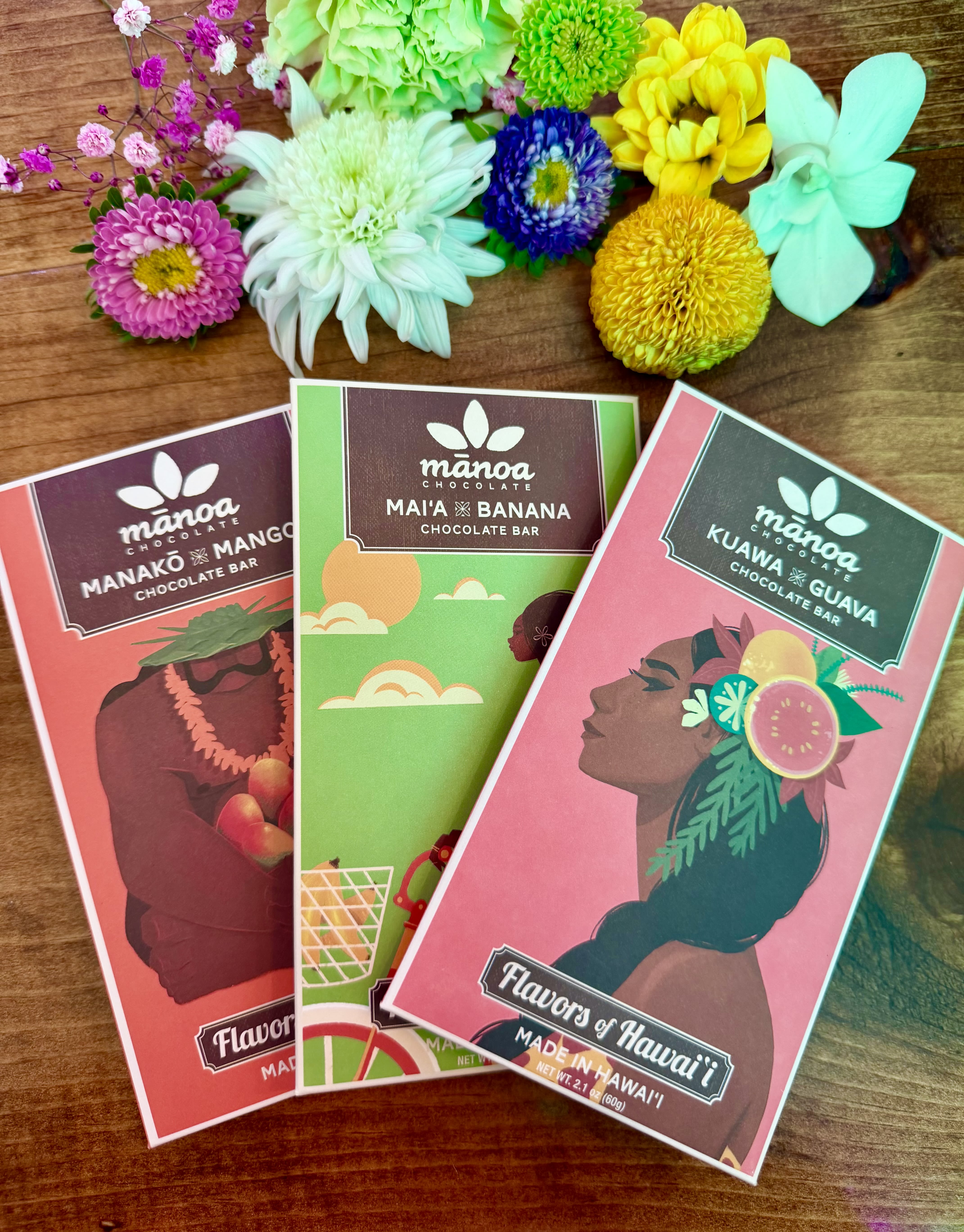 Three chocolate bars with colorful flower accents on a wooden surface.