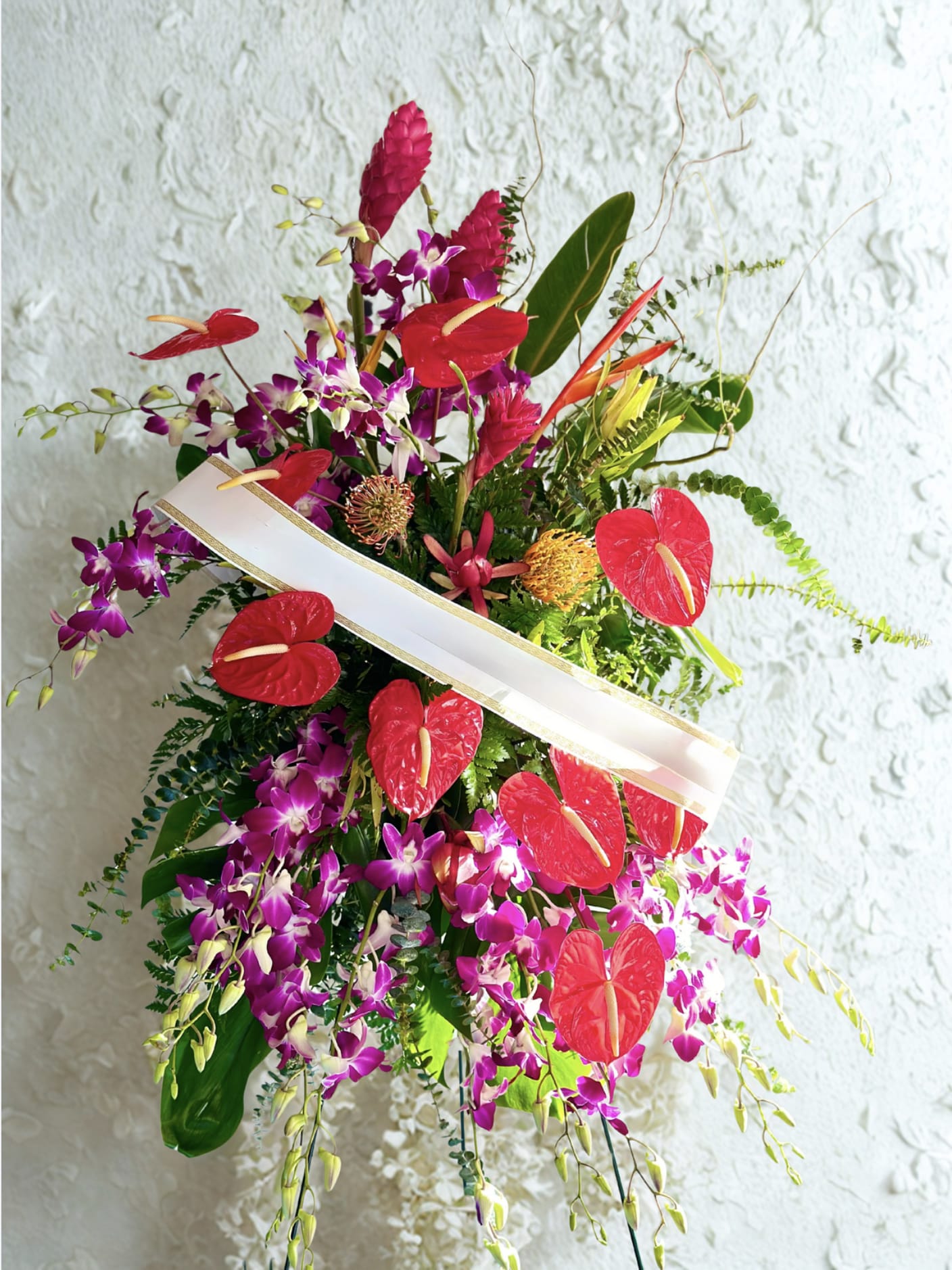 Tropical floral arrangement with red anthuriums and purple orchids