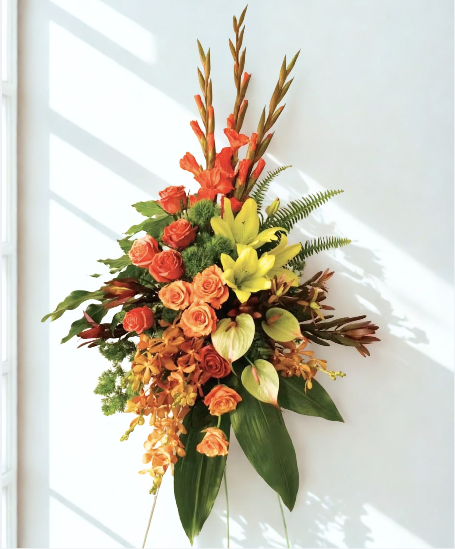 Tall floral arrangement with orange roses and yellow lilies